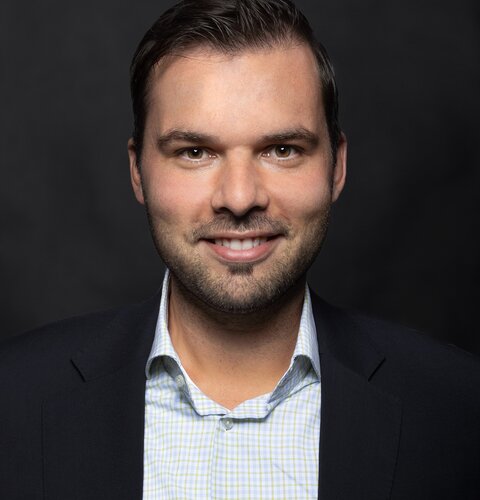 Marco Luciano Das Bild zeigt ein Porträt von Marco Luciano. Er trägt ein Hemd und Sakko. Er hat dunkle Haare und lächelt in die Kamera.