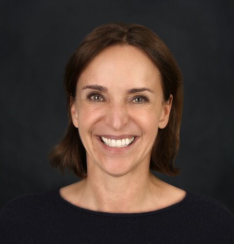 Sylvia Piske | © wob AG Dieses Bild ist ein Porträt von Sylvia Piske. Sie hat dunkle Haare, die fast bis zu den Schultern reichen. Sie lächelt in die Kamera. Sie trägt ein schwarzes Oberteil. Der Hintergrund ist dunkel. | © wob AG