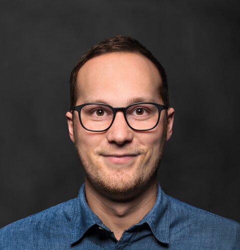 Thorsten Petersen | © wob AG Das Bild ist ein Porträt von Thorsten Petersen. Er hat eine Brille und ein hellblaues Hemd an. Der Hintergrund ist dunkel. | © wob AG