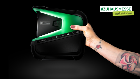 Keyvisual #ZUHAUSEMESSE Werkstattshow Dieses Bild zeig einen tätowierten Arm, der den mega macs X vor einem schwarzen Hintergrund hält. Mit diesem Motiv wurde ein digitales Event kommuniziert, das von der in den Zielgruppen sehr bekannten und beliebten Lina van de Mars moderiert wurde – die Tätowierungen waren ein Hinweis darauf.