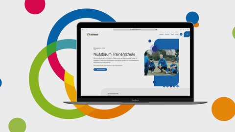 Website Nussbaum Medien Zu sehen ist ein Laptop mit der neuen Homepage von Nussbaum. Der Laptop scheint vor einem hellen Hintergrund zu schweben. Auf dem hellen Hintergrund sind Farbpunkte, die auch in dem Erscheinungsbild von Nussbaum auftauchen. Zusätzlich ist die Bildmarke von Nussbaum hinter dem Laptop zu sehen.